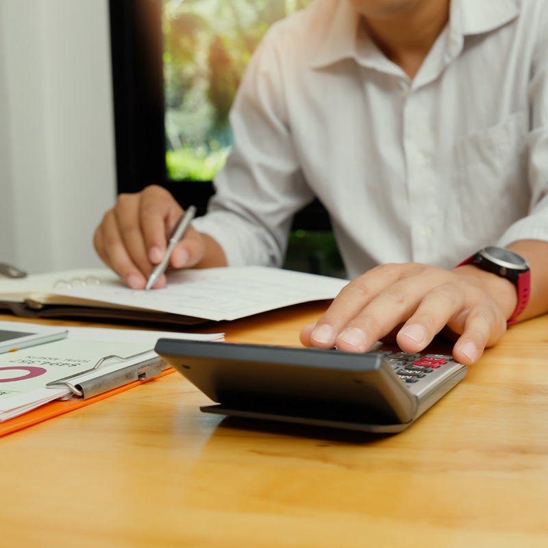 Person performing accounting services using calculator at desk